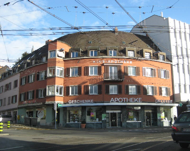 Klus Apotheke am Klusplatz Zürich Hirslanden Stadtkreis 7. Das markante runde rote Eckhaus ist so etwas wie das Wahrzeichen des Klusplatzes.